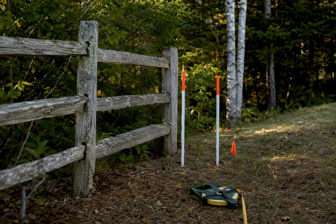 Fence line beside Maine survey stakes
