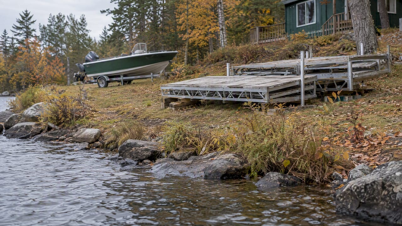 Removed dock sections stored above a Maine lake shoreline